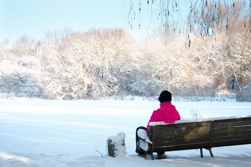 Billede af dame med pink jakke, der sidder på ern bænk i sneen.