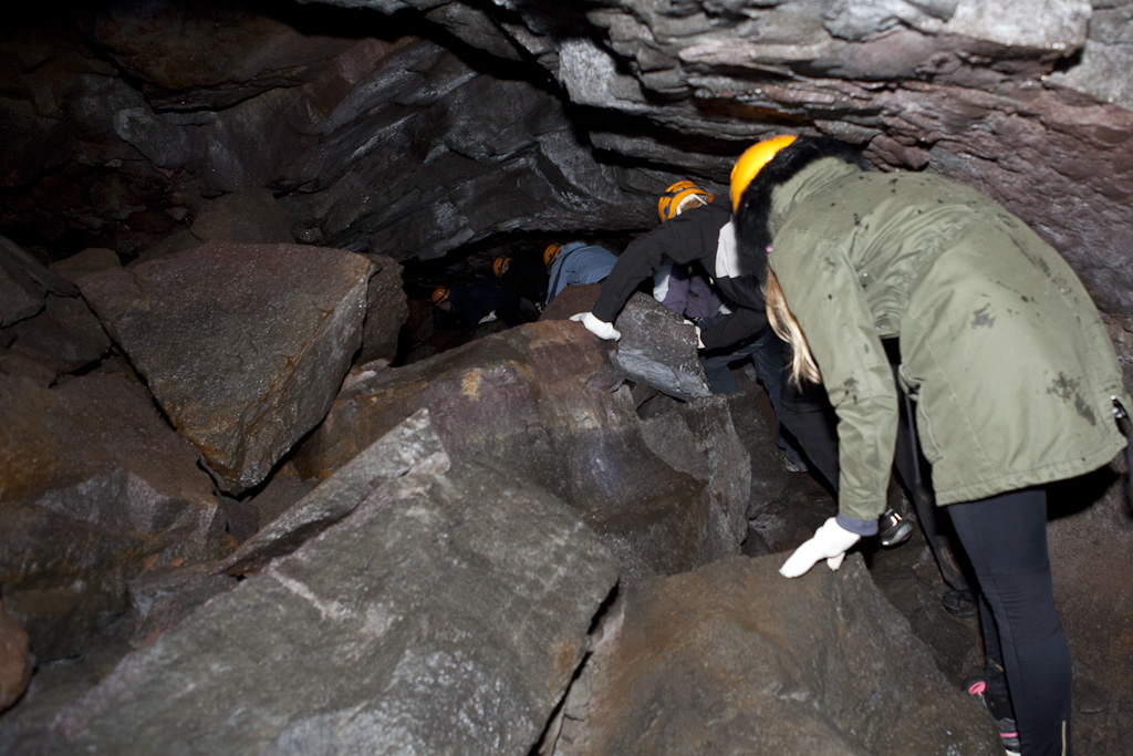 Folk der kravler rundt på lavabrokker i grotten